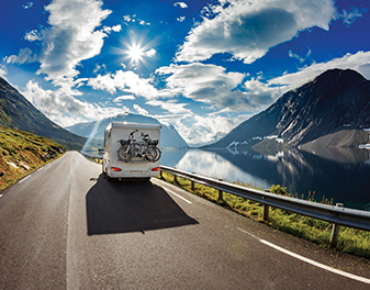 A caravan casting a large shadow while driving through a valley