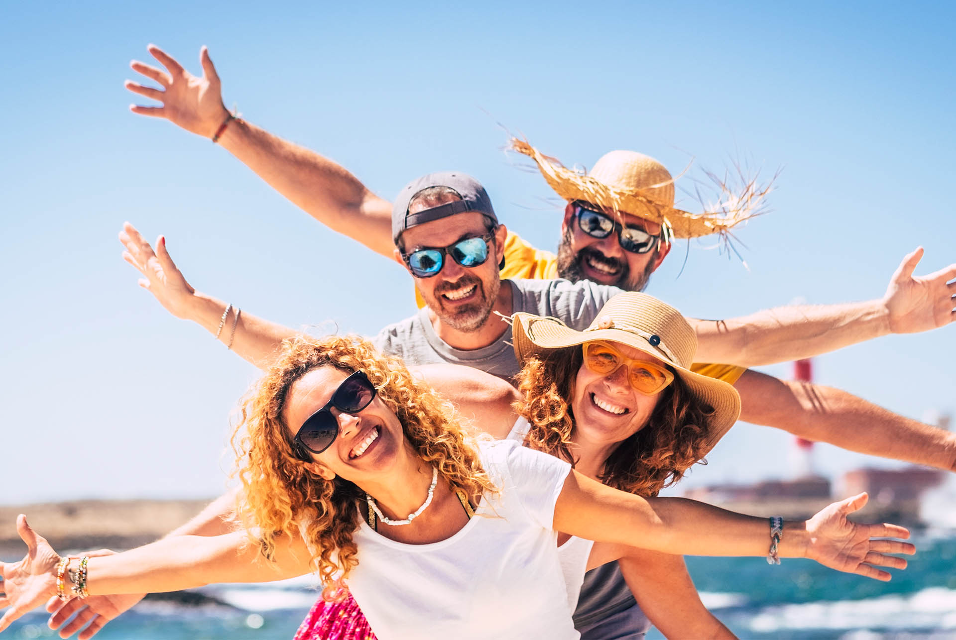 Happy group of people on vacation at the beach with arms spread out